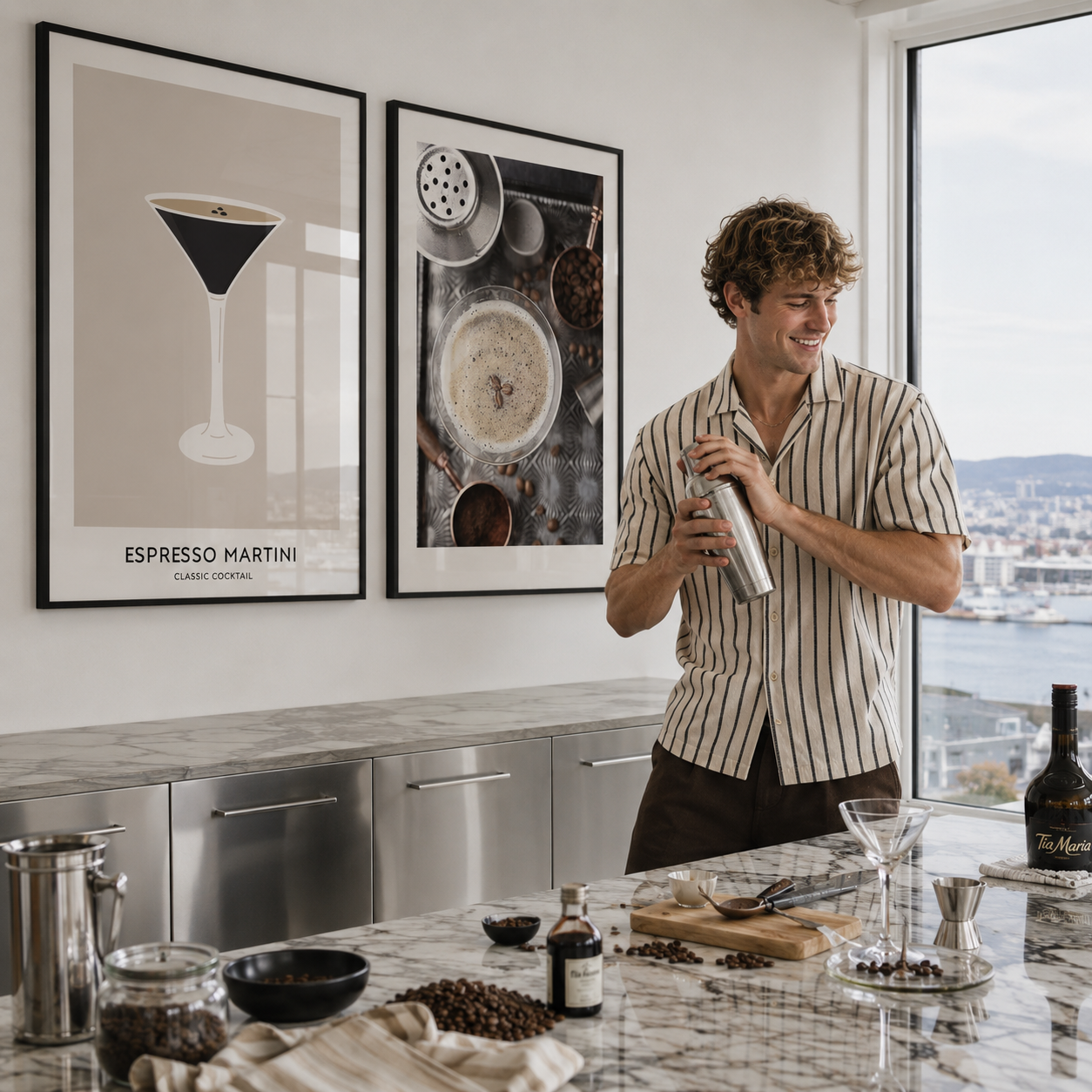 Man in a kitchen holding a cocktail shaker with framed art on the wall.