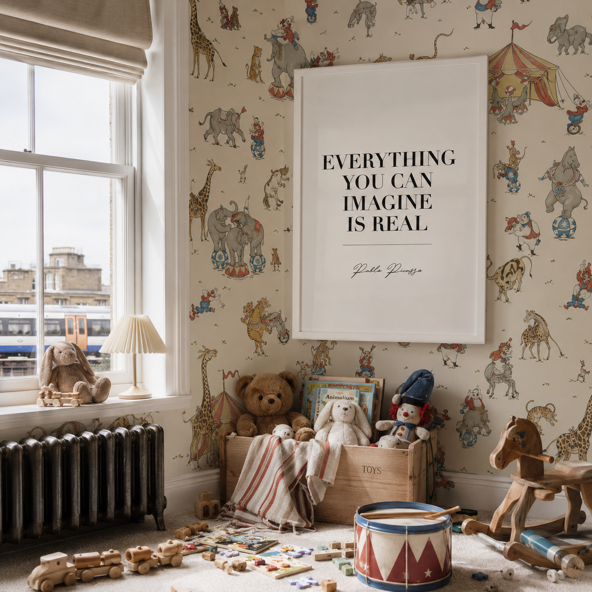 A styled children's room corner with patterned wallpaper, a large white framed wall print reading 'EVERYTHING YOU CAN IMAGINE IS REAL' with 'Pablo Picasso' below it, toys on the floor, a window, and a radiator.