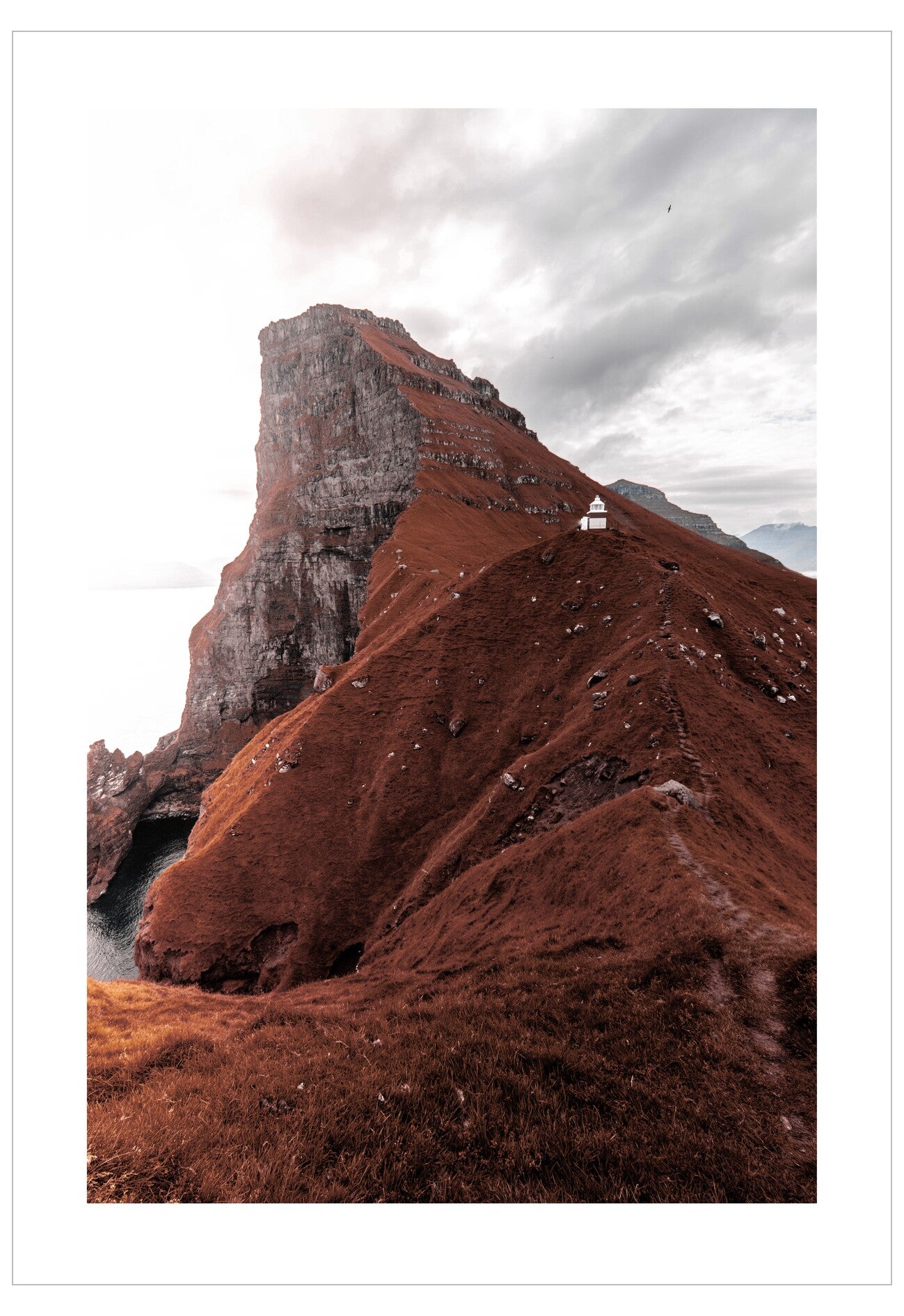Red rock formation with a small white building on a cloudy day