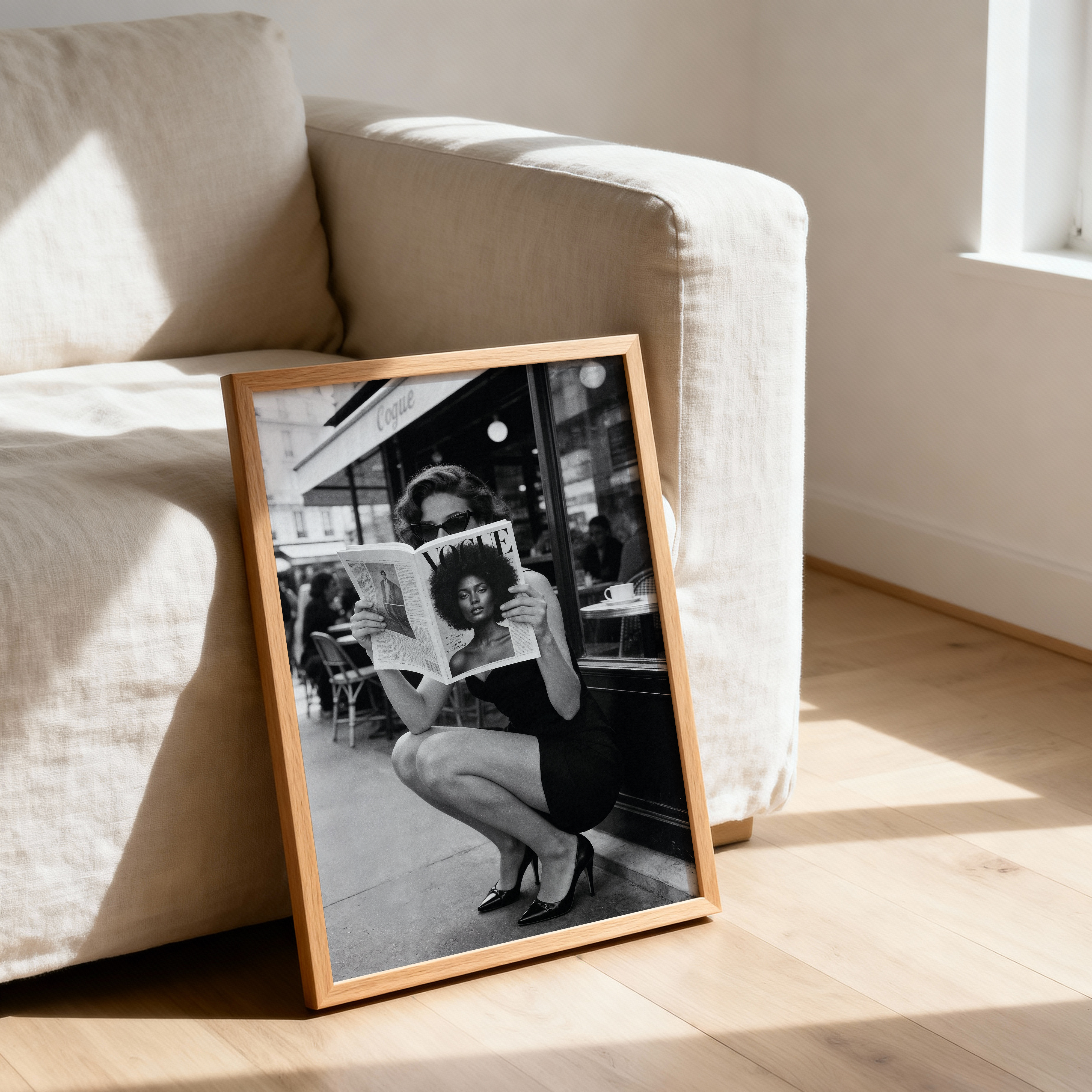 Framed black and white photo of a woman reading a newspaper on a wooden floor.