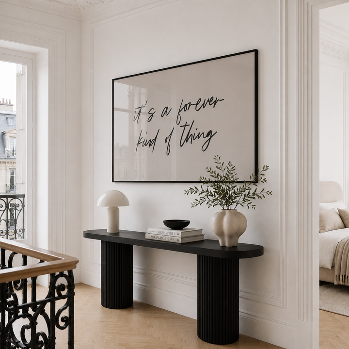 Modern interior with a black console table, decorative items, and a framed quote on the wall.