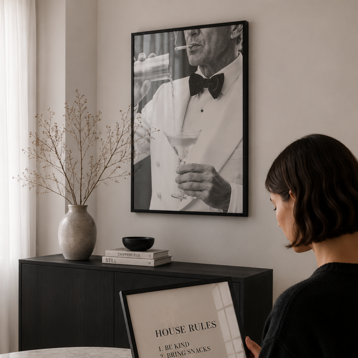 Woman reading a book titled 'House Rules' in a cozy room with a framed picture on the wall.