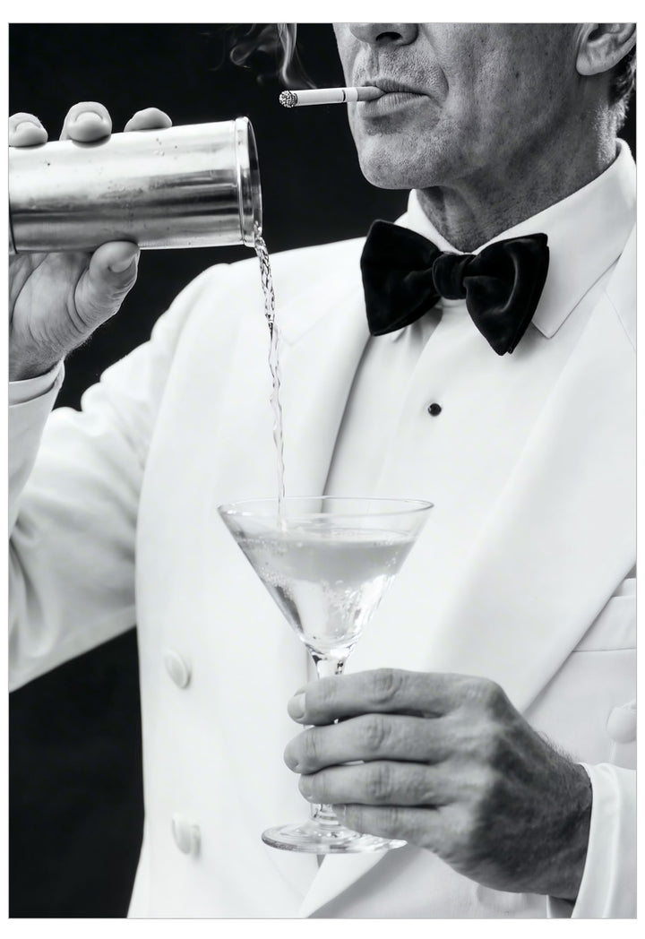 Man in a tuxedo pouring a cocktail into a glass with a cigarette in his mouth.