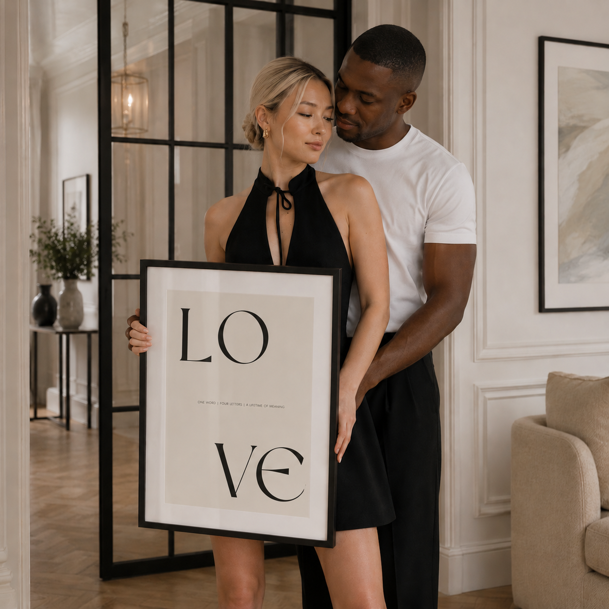 Couple holding a framed picture with 'LOVE' in a stylish interior setting