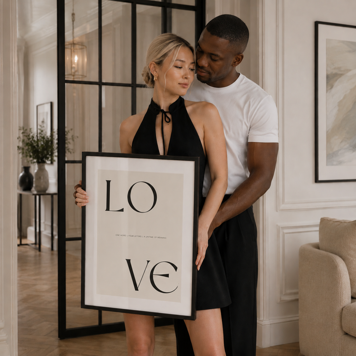 Couple holding a framed picture with 'LOVE' in a stylish interior setting