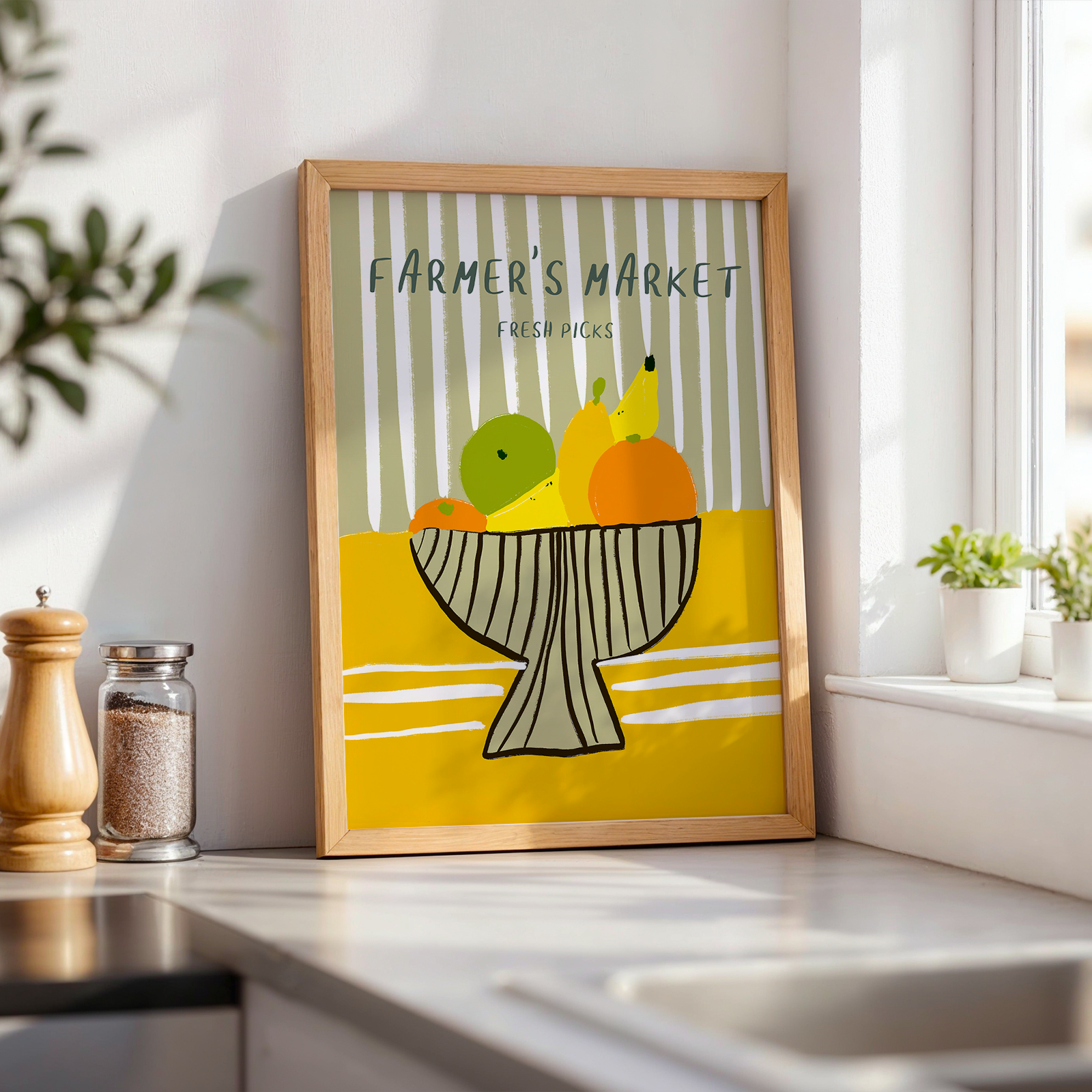 Framed artwork of a bowl of fruits on a kitchen counter with a window in the background