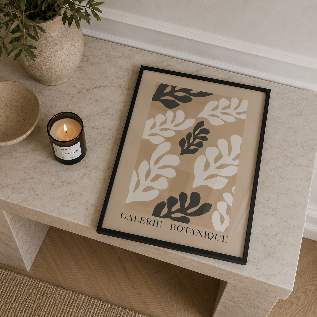 Framed botanical art print on a table with a candle and plant in the background