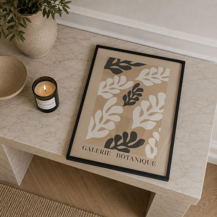Framed botanical art print on a table with a candle and plant in the background