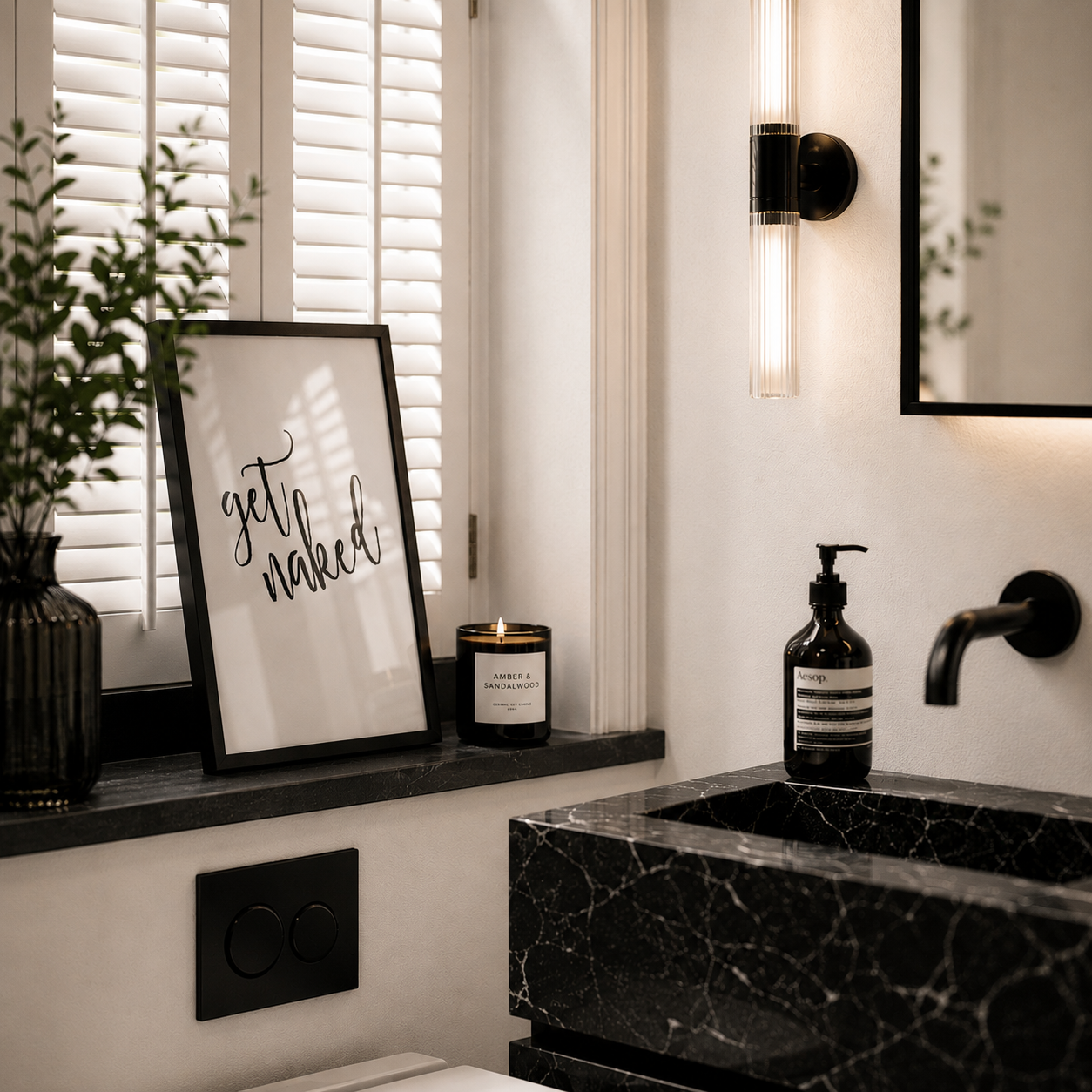 Bathroom interior with a black marble sink, framed artwork, and decorative items.