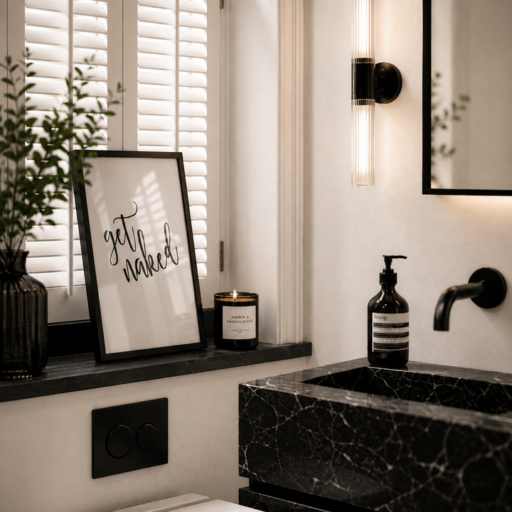 Bathroom interior with a black marble sink, framed artwork, and decorative items.
