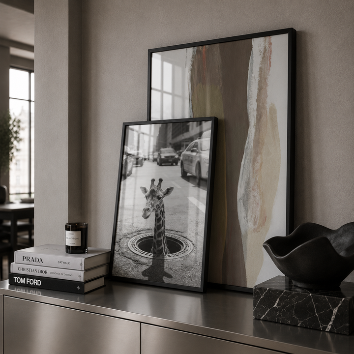 Framed artwork on a shelf with books and decorative items.