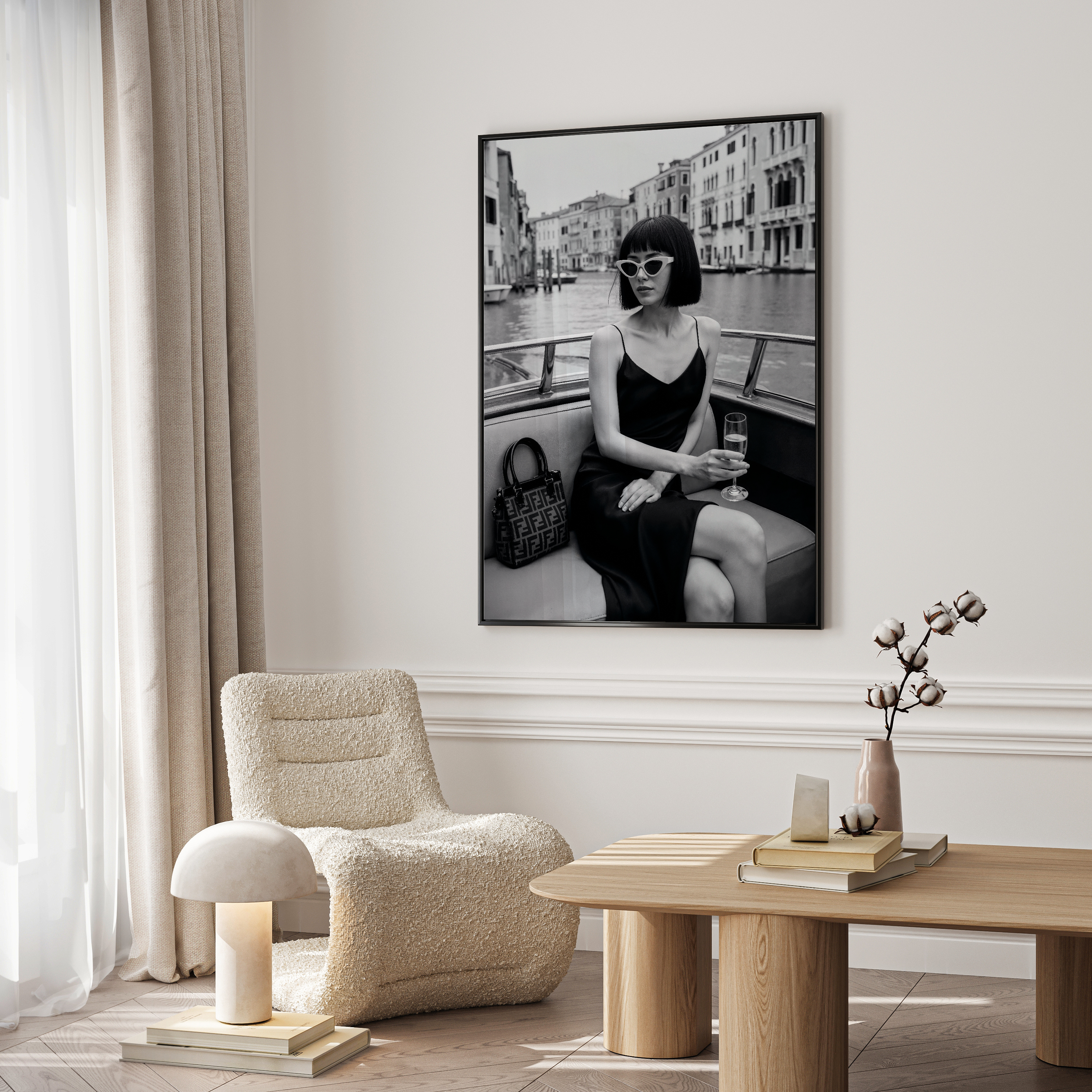 Modern living room with a framed black and white photograph of a woman on a boat, a beige armchair, and a wooden coffee table.