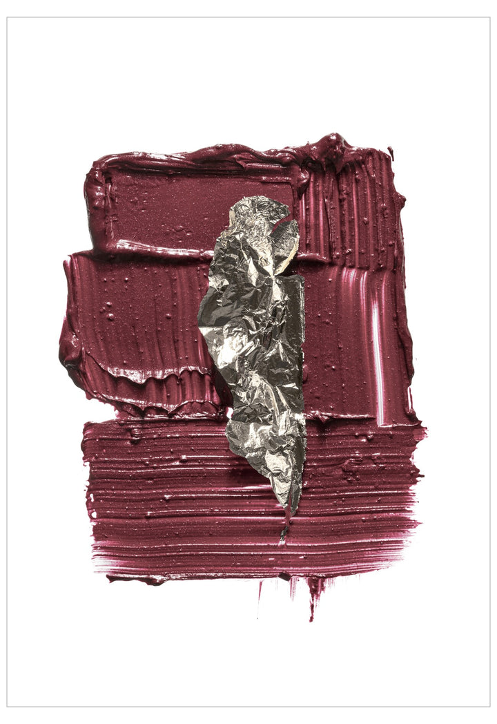 Close-up of a maroon lipstick with a leaf on a white background
