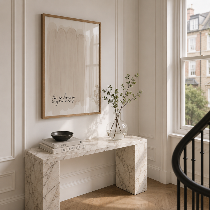 Marble console table with books and a vase in a room with a framed picture on the wall.