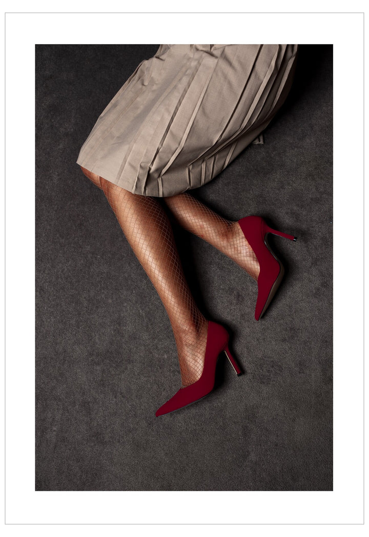 Red high heels worn with a beige skirt on a dark surface
