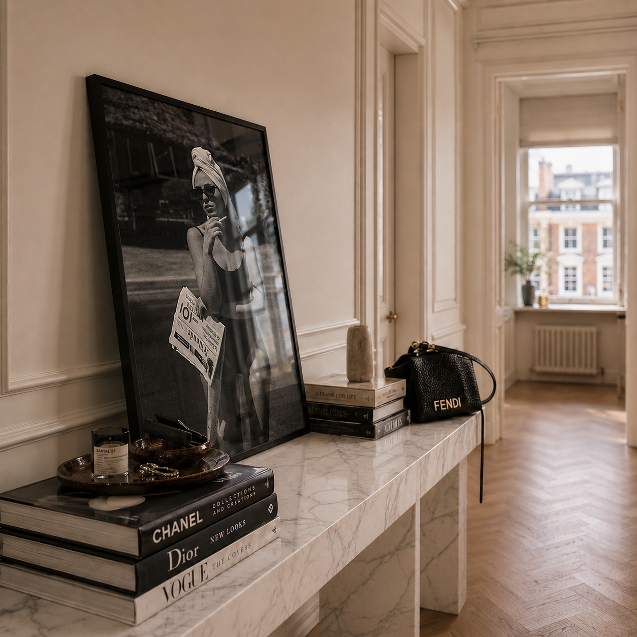 Framed artwork on a marble ledge with books and a handbag in a stylish room.