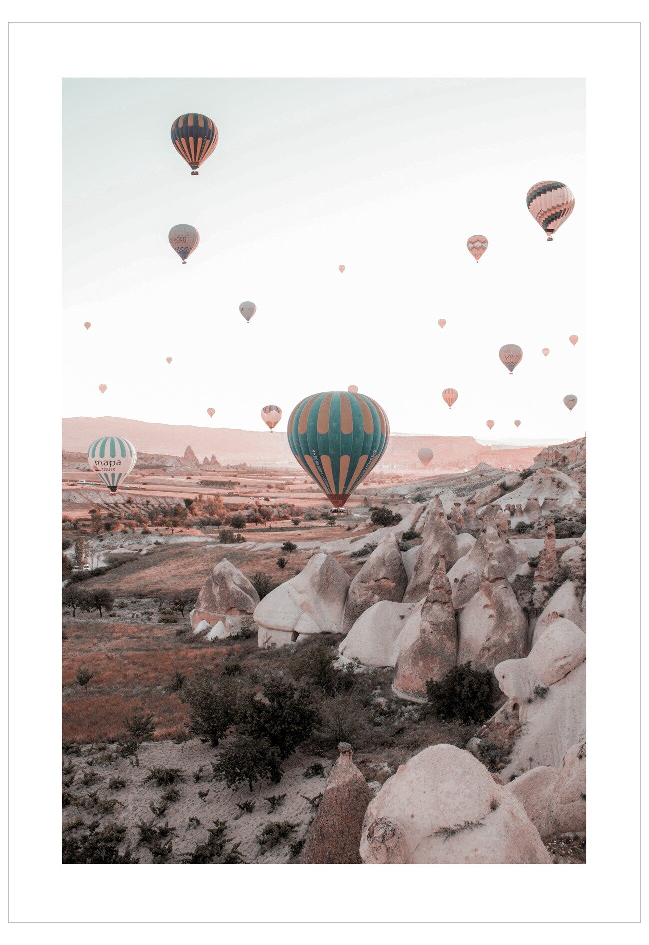 Hot air balloons floating over a rocky landscape with a pinkish hue.