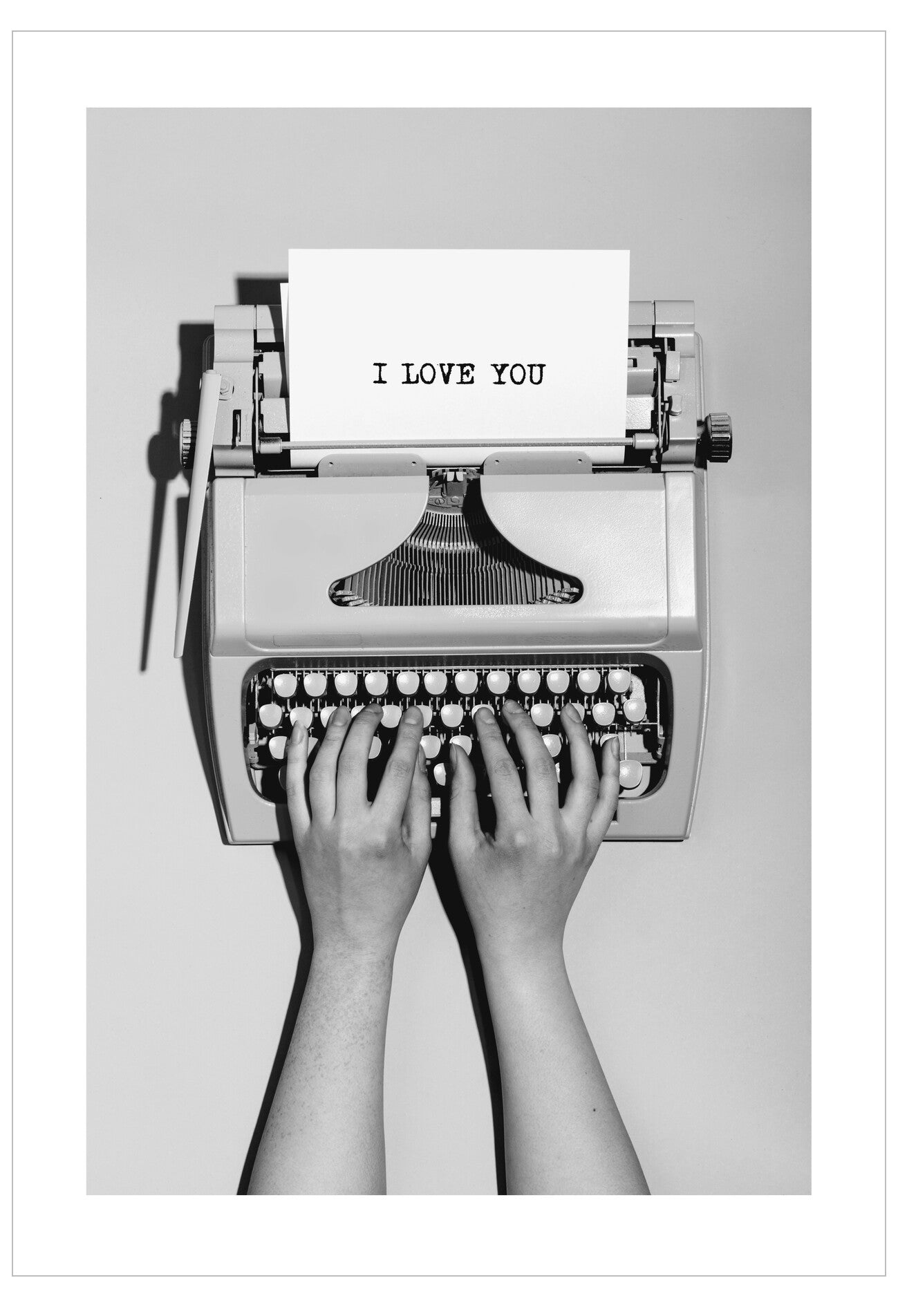 Typewriter with 'I LOVE YOU' paper and hands typing on a white background