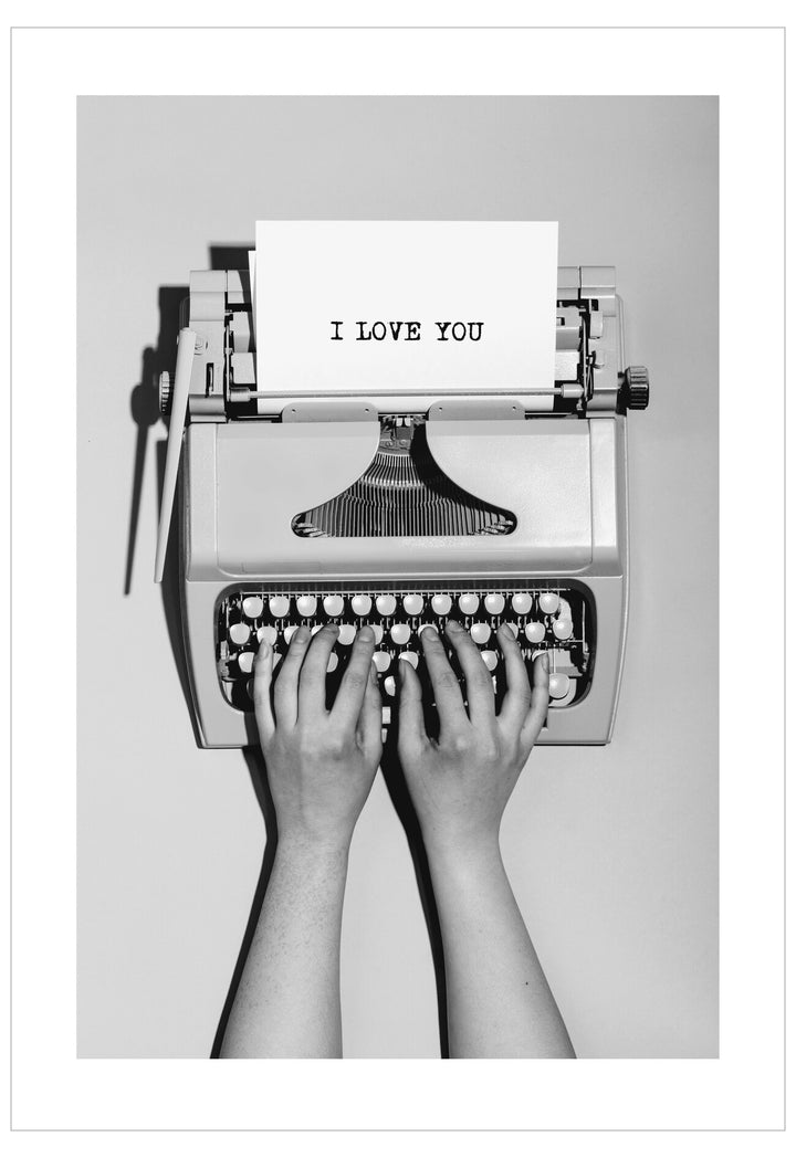 Typewriter with 'I LOVE YOU' paper and hands typing on a white background