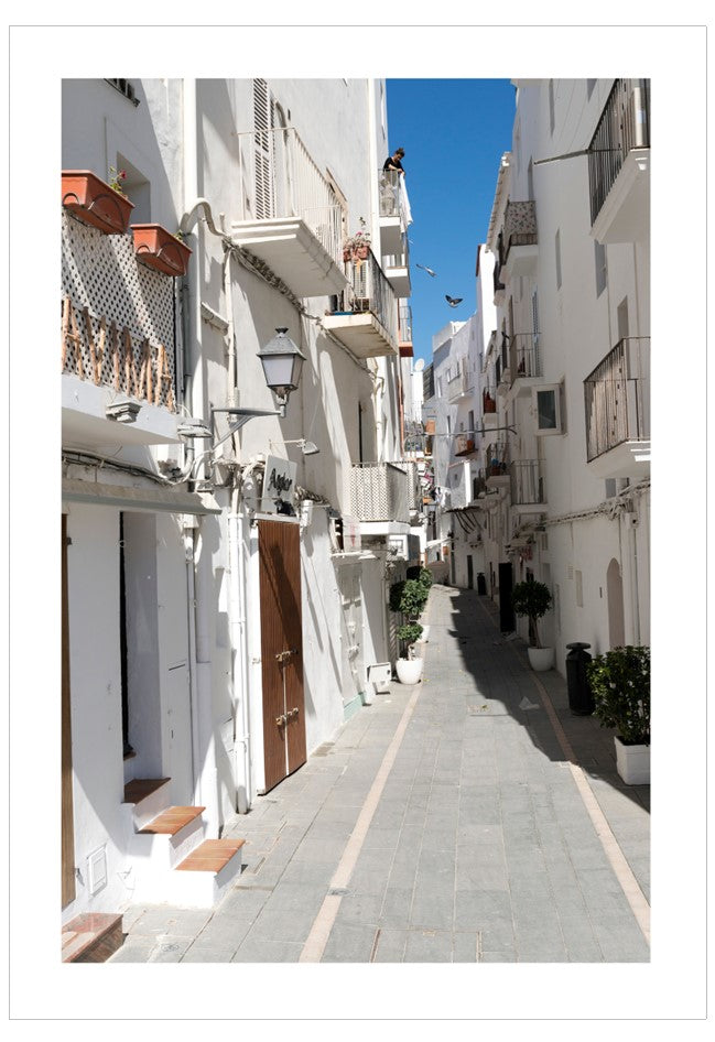 Tight street between white buildings with blue sky