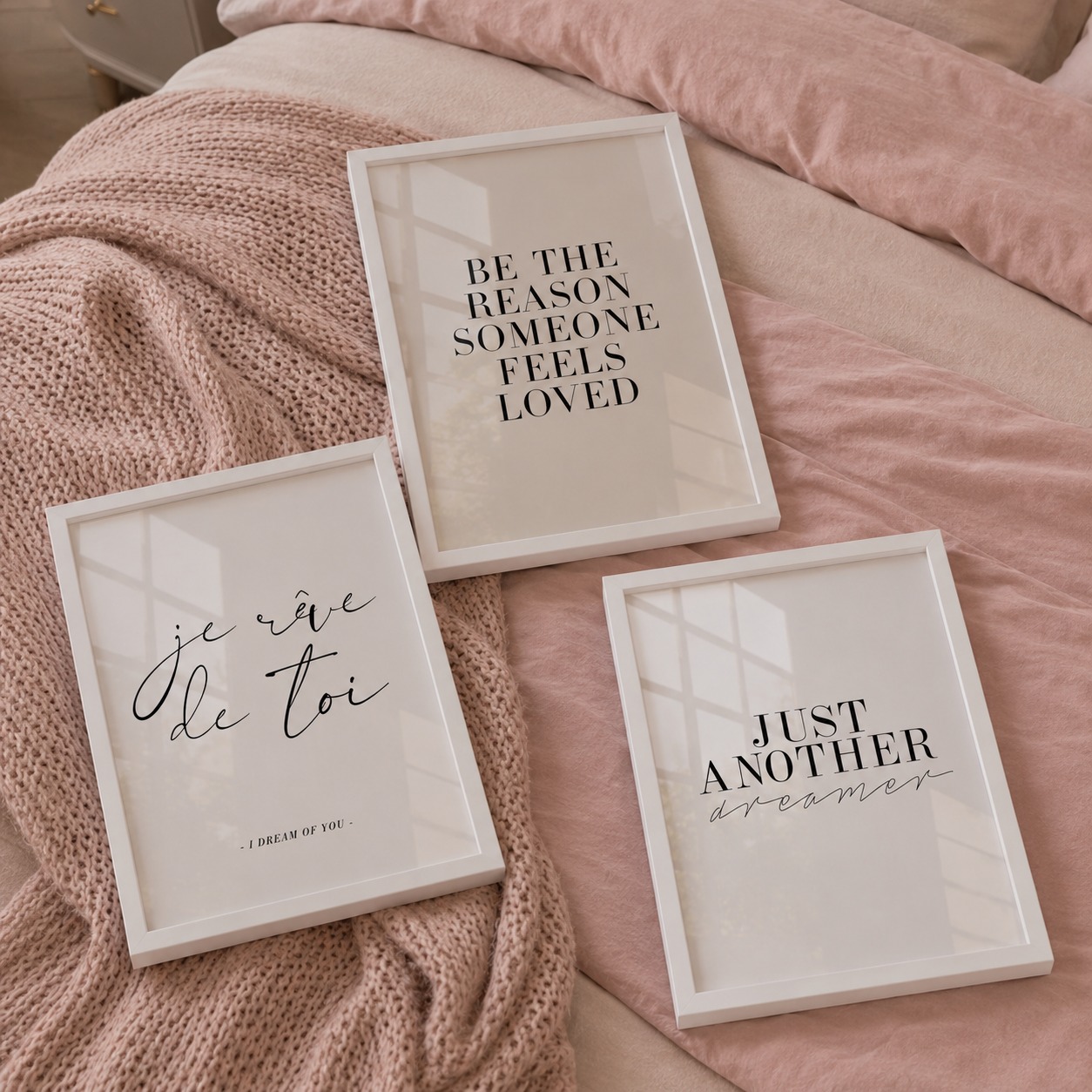 Three framed quotes on a bed with pink bedding