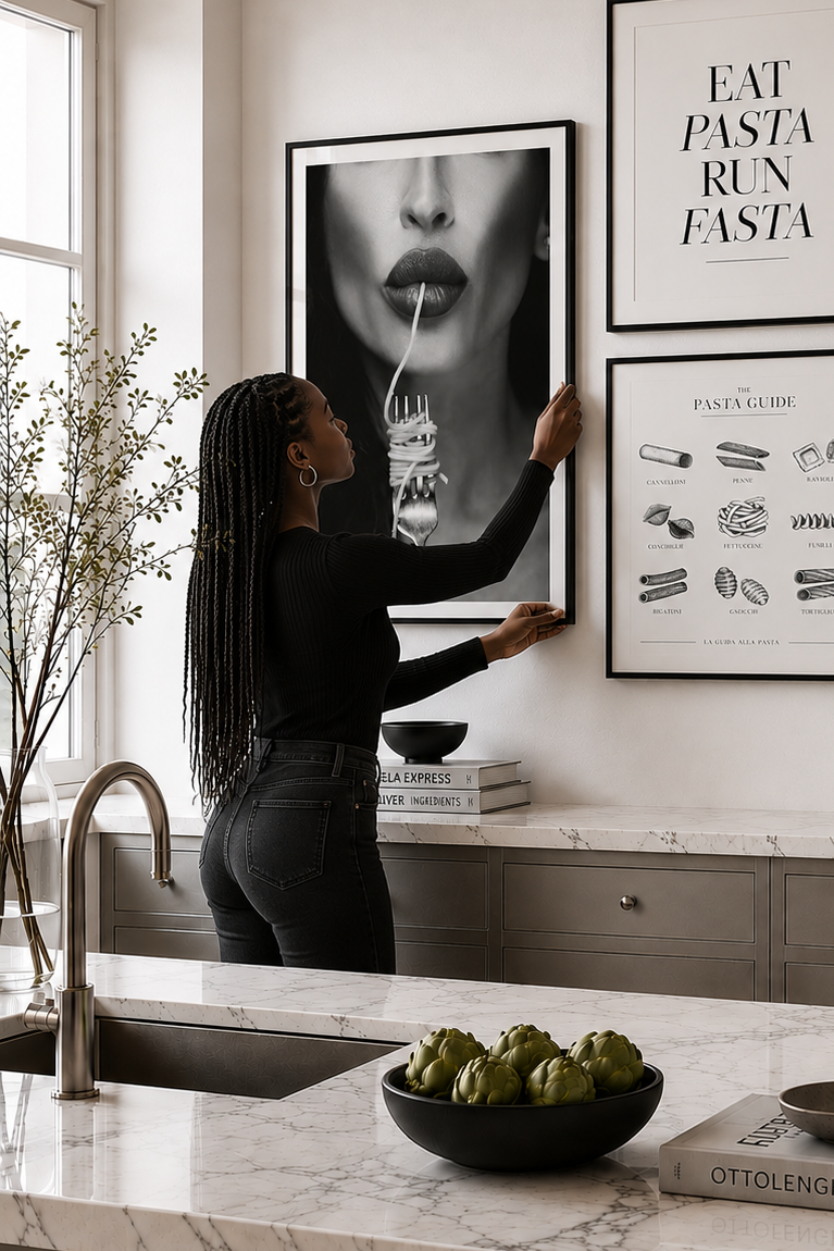 Woman arranging framed art prints on a kitchen wall