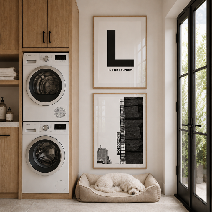 Modern laundry room with stacked washer and dryer, framed art, and a dog bed.