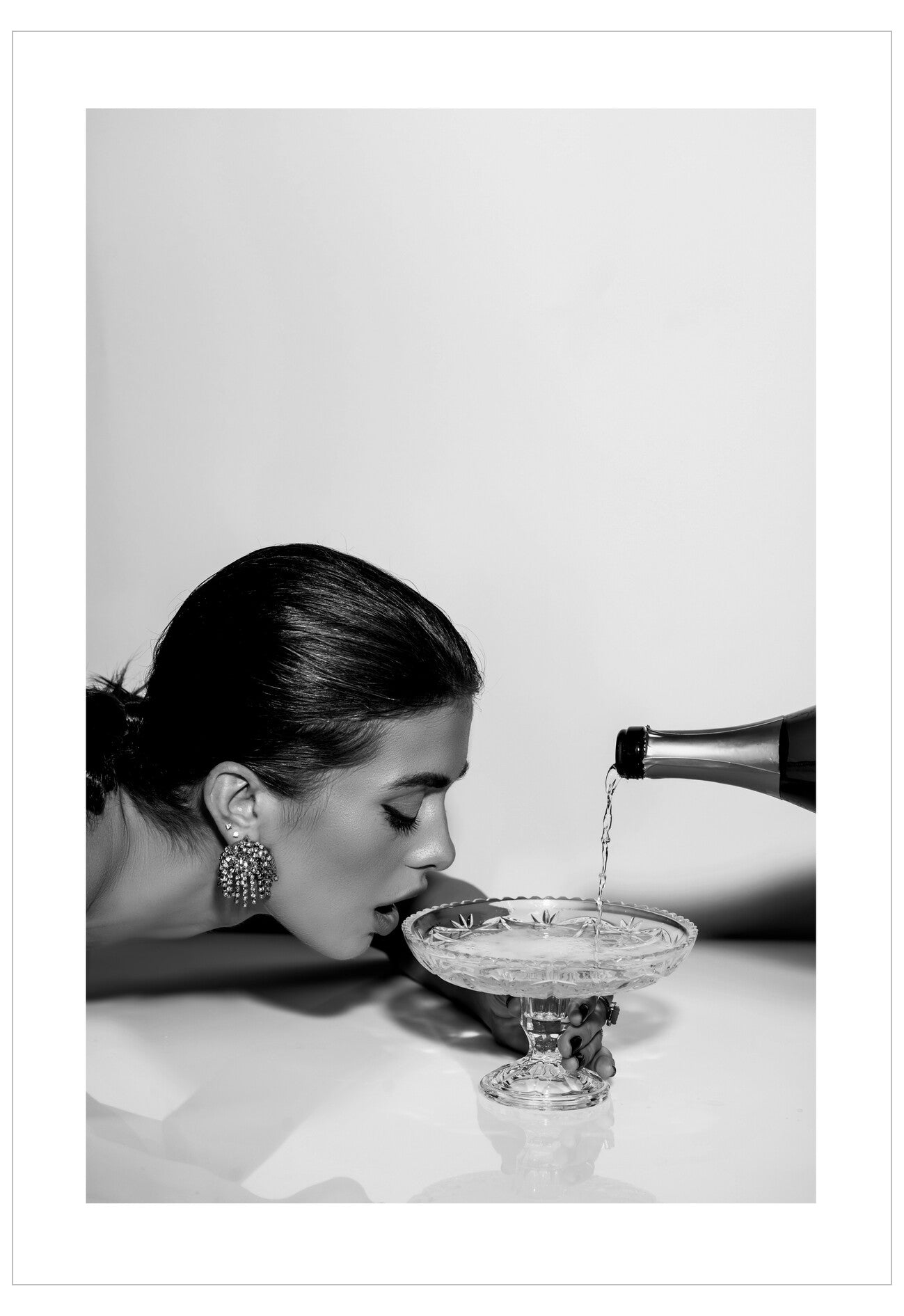 Woman pouring champagne into a glass with a bottle in hand, black and white photo.