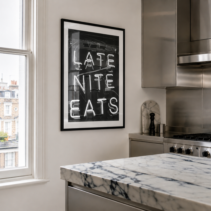 Modern kitchen with marble countertop, stainless steel appliances, and framed artwork on the wall.