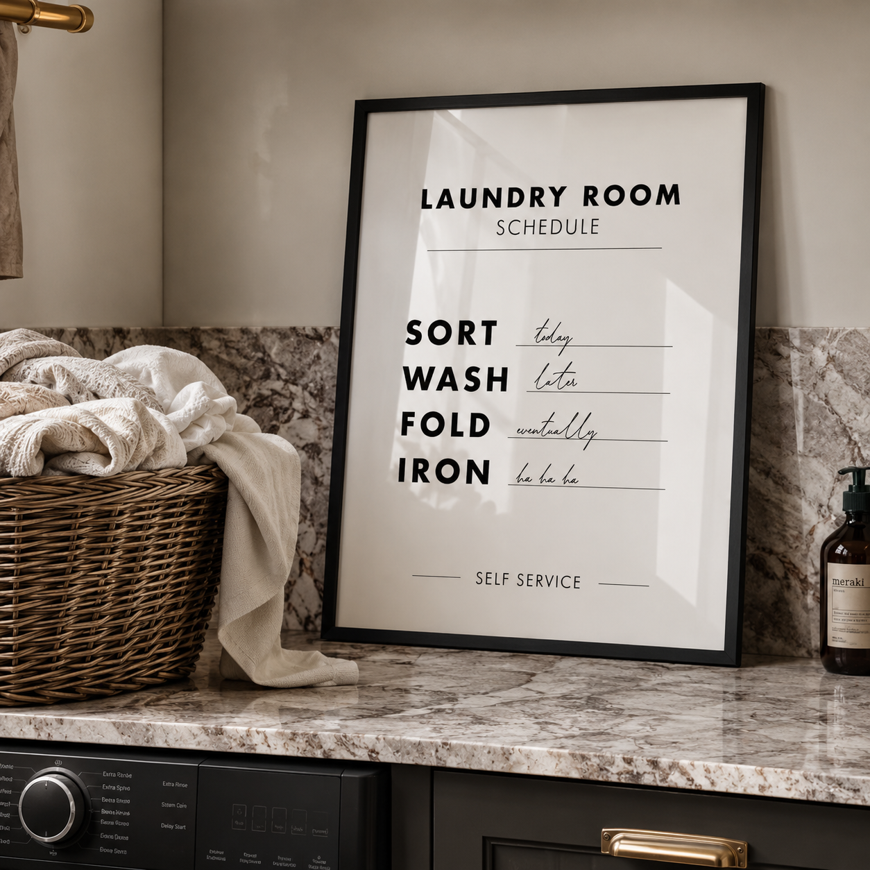 Framed laundry room schedule poster on a counter with a basket of clothes and laundry detergent.