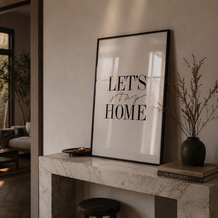 Framed poster with 'Let's Stay Home' text on a marble console table.