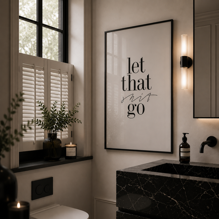 Bathroom interior with a framed quote on the wall, black marble sink, and window with shutters.