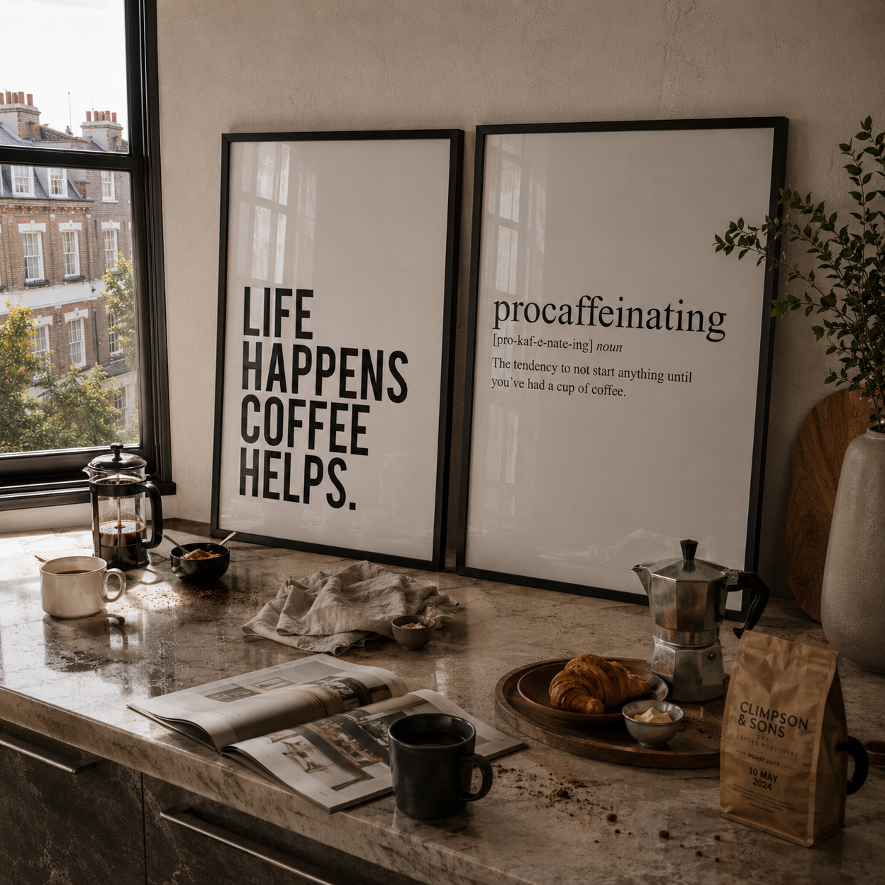 Kitchen counter with coffee-making items, framed posters, and a window view.