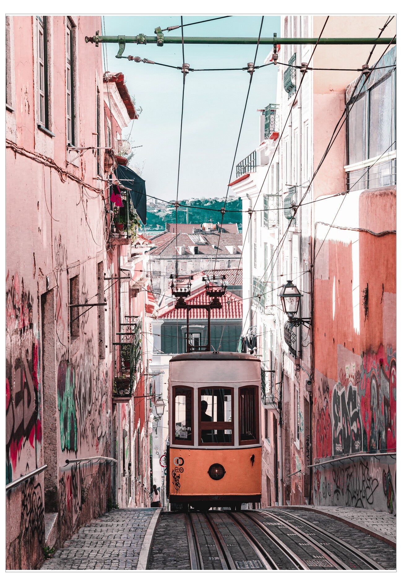 Orange tram in a narrow street flanked by pink buildings with graffiti
