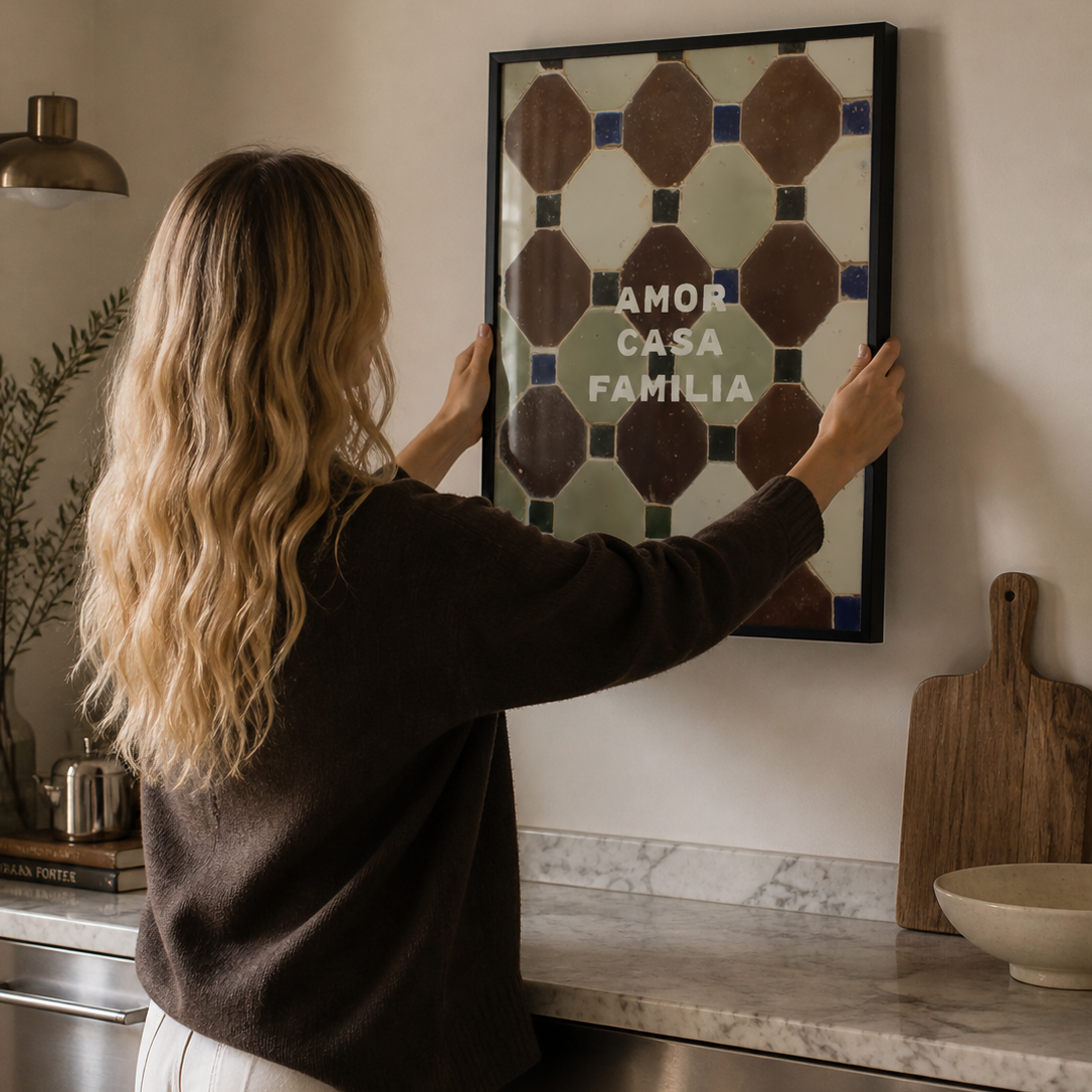 Woman hanging a framed artwork on a wall in a kitchen.