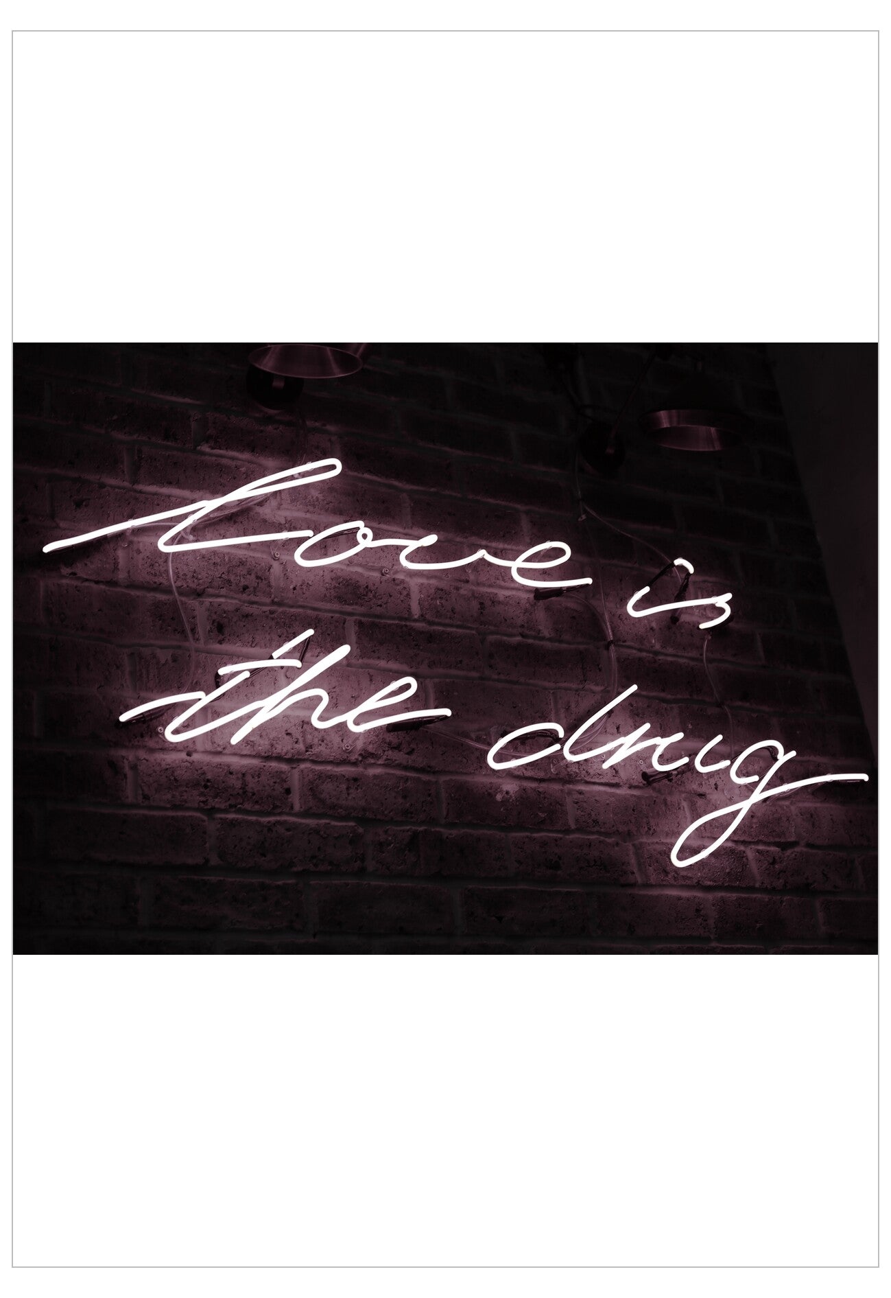 Neon sign with 'Love is the drug' on a brick wall