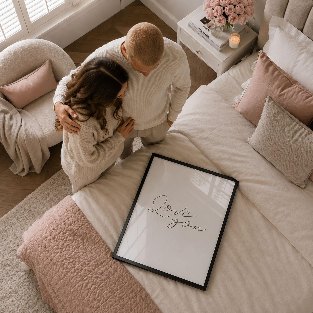 Couple embracing on a bed with a 'Love you' sign in a cozy bedroom.