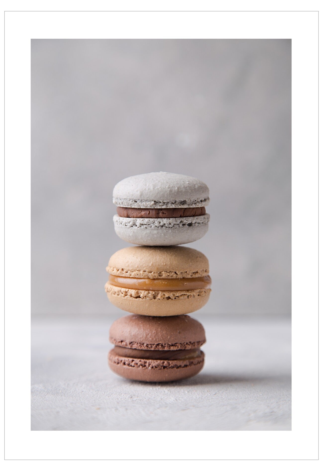 Stack of three macarons on a light gray background