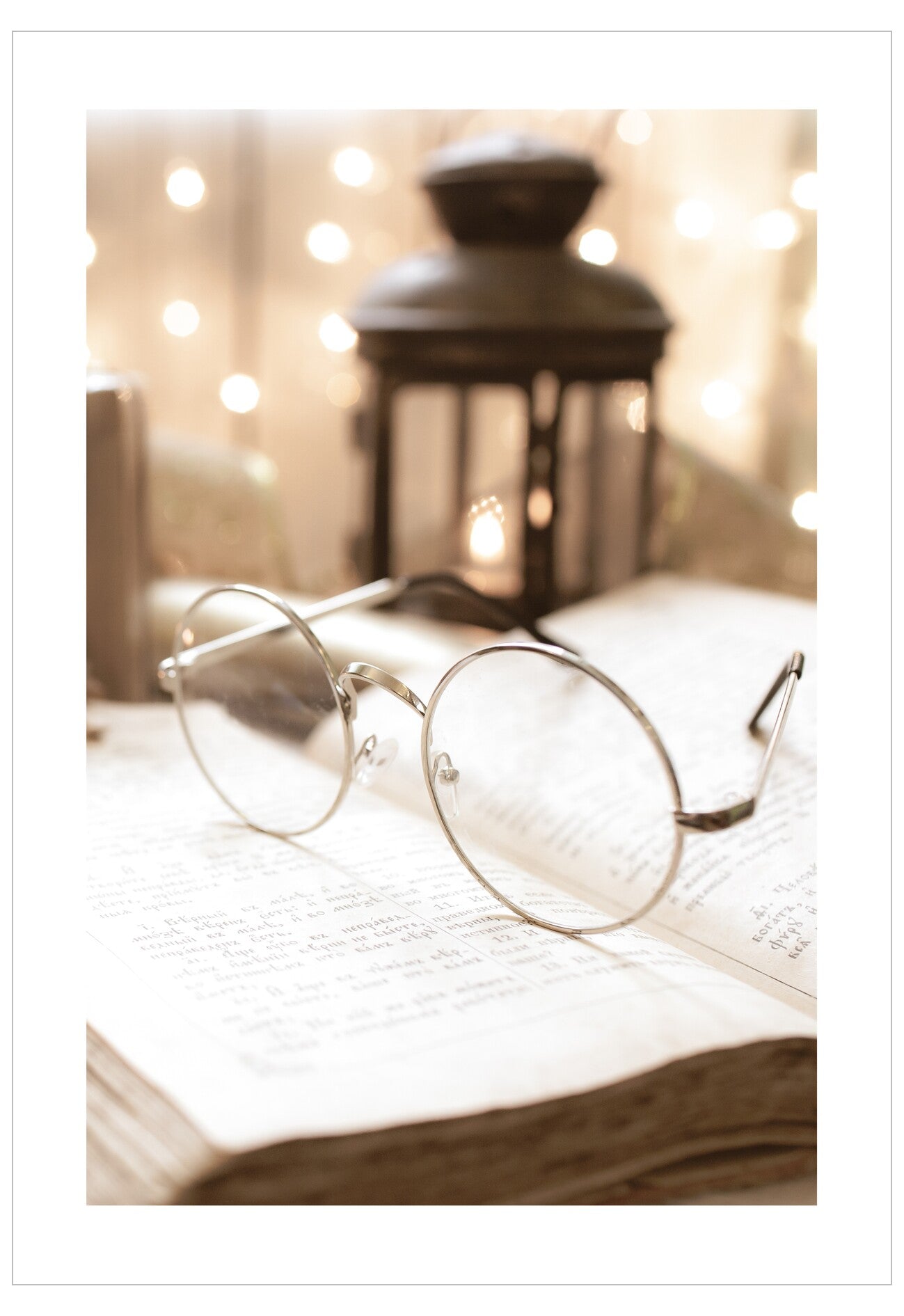 Round glasses on an open book with a blurred lantern and lights in the background