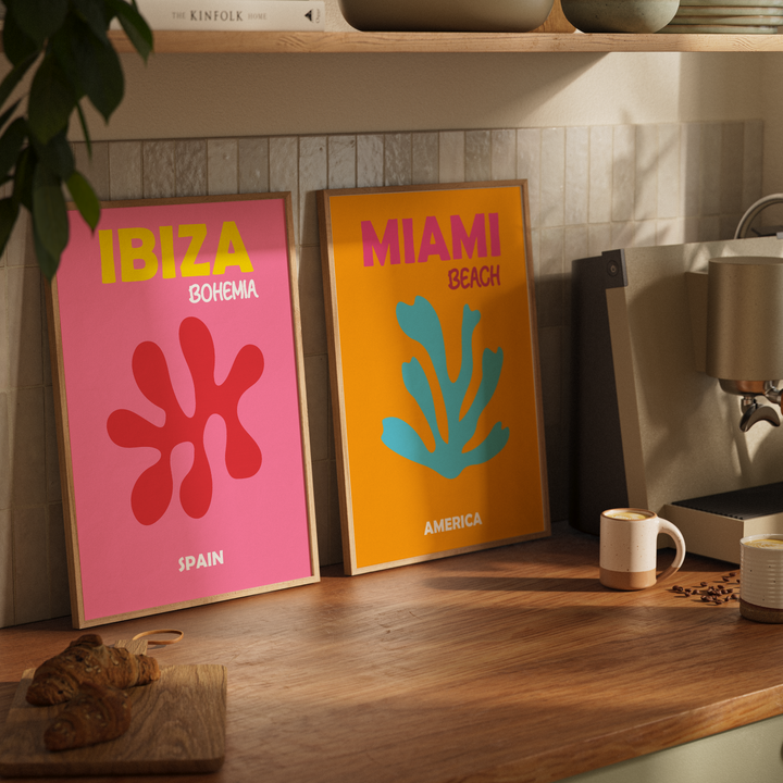 Two colorful posters on a kitchen counter with a coffee machine and coffee beans in the background.