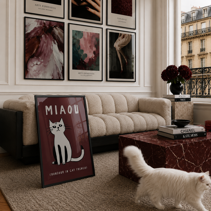 Living room with a beige sofa, framed art on the wall, and a cat walking on the floor.