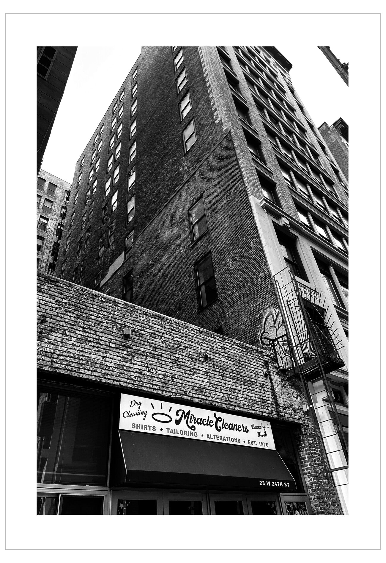 Black and white photo of a city street with a building facade and sign.