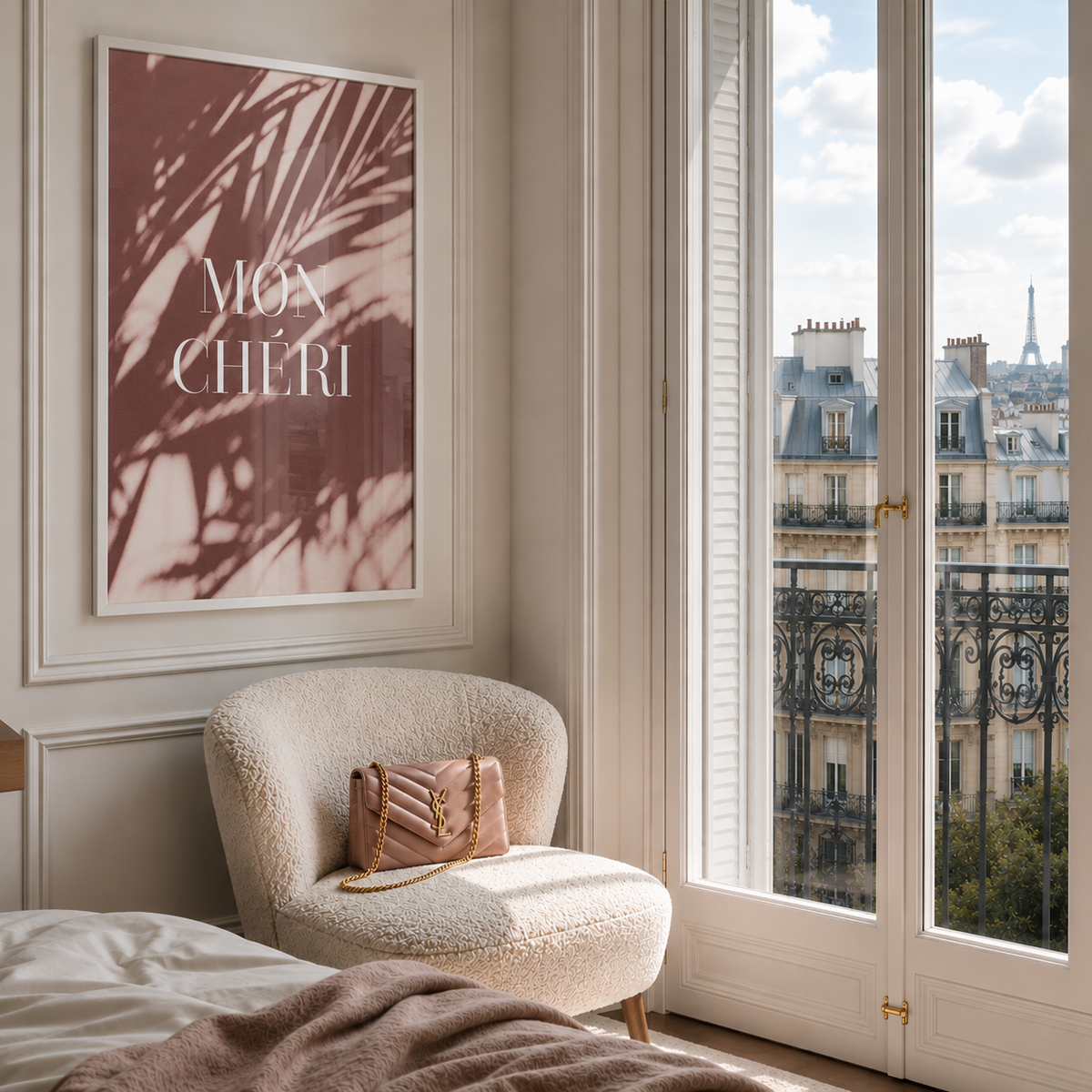 A framed wall art print featuring a dusty rose and brown palm shadow pattern with the text 'MGA CHERI' in white, displayed in a bright bedroom corner next to a window with a view of Paris rooftops. A cream boucle armchair with a pink handbag sits below the artwork.