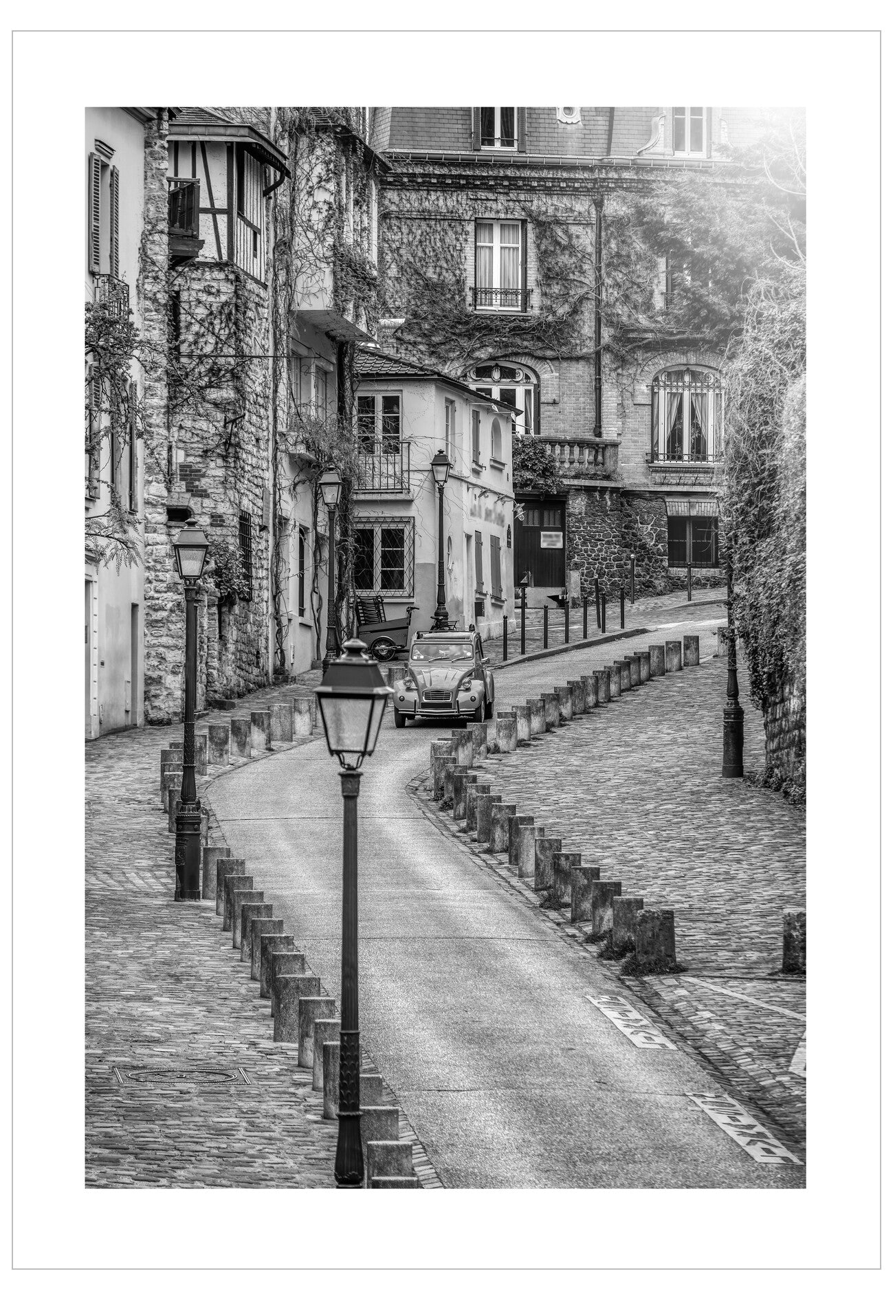 Black and white street scene with old buildings and a car in a European town.