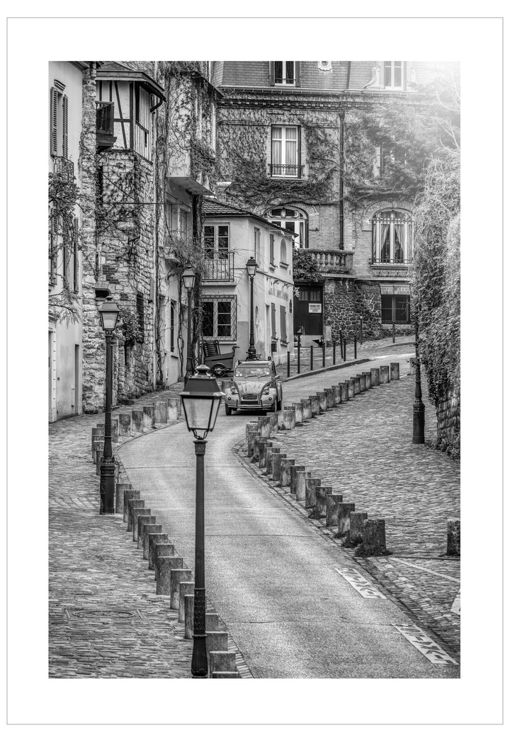 Black and white street scene with old buildings and a car in a European town.