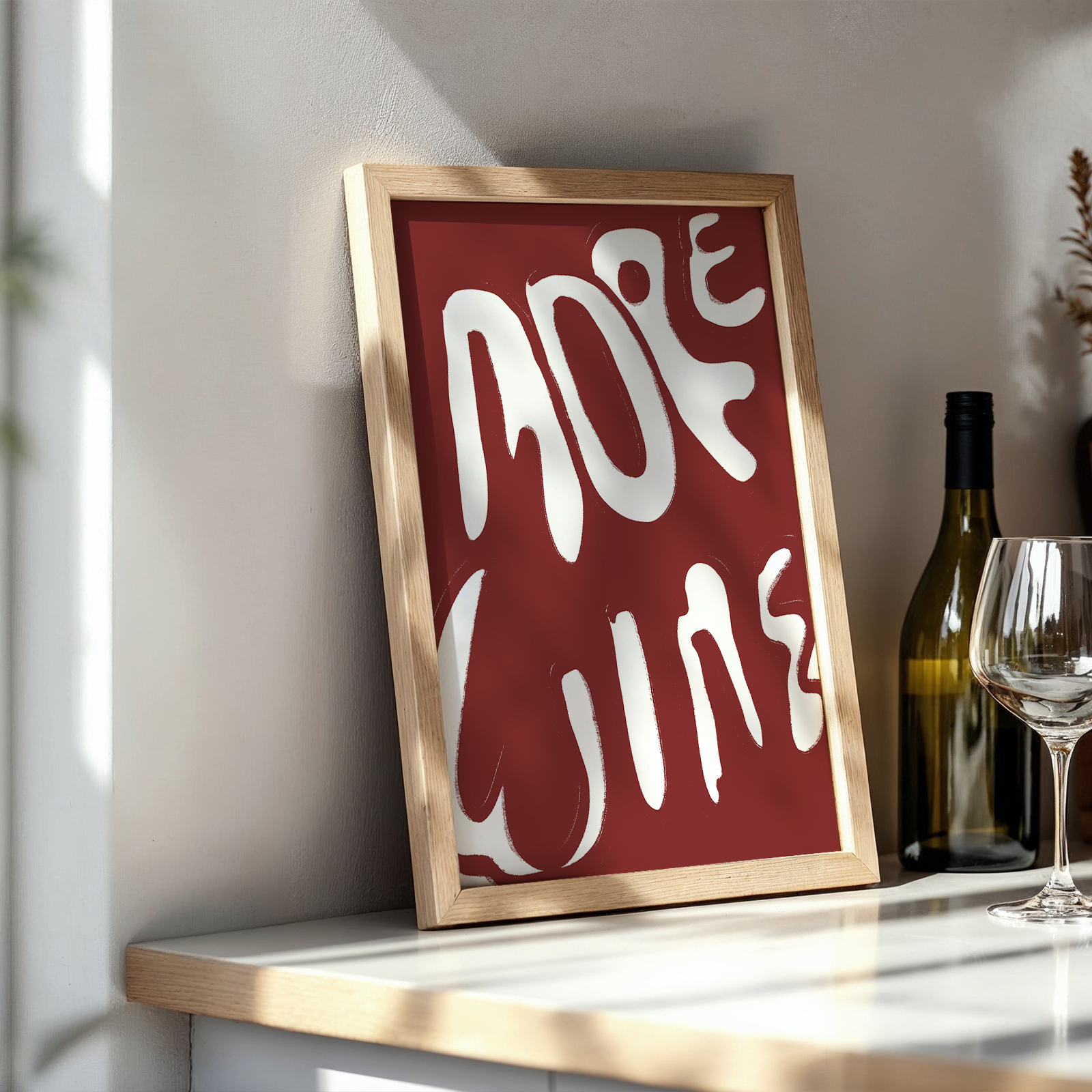 Framed artwork with 'More Wine' text on a shelf with wine-related items.