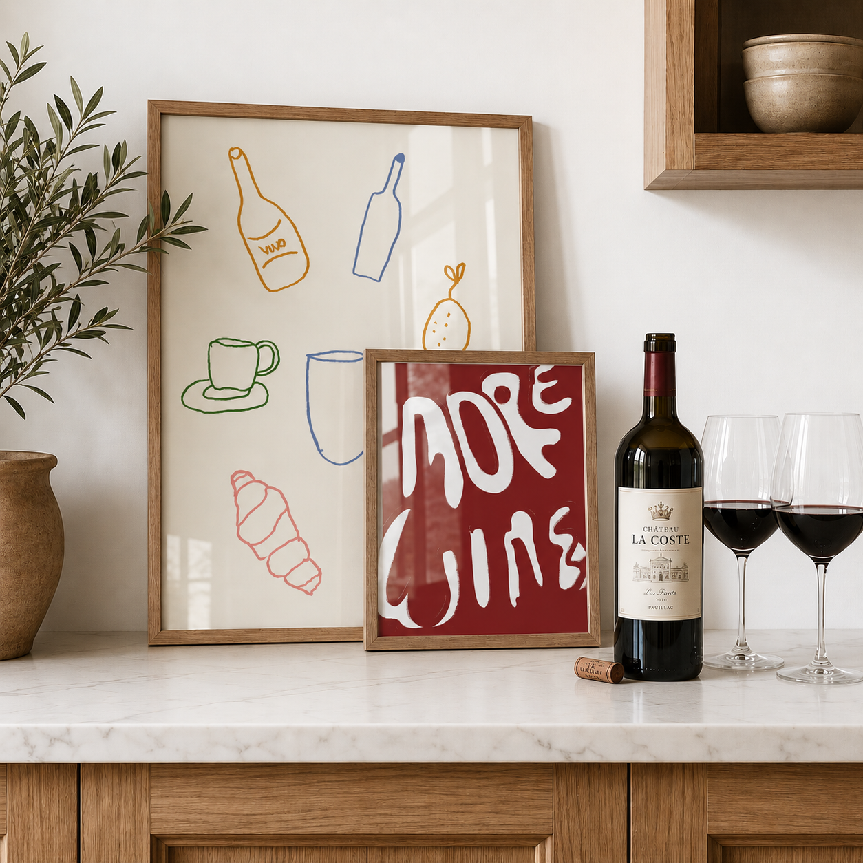 Framed artwork on a kitchen counter with a bottle of wine and glasses.