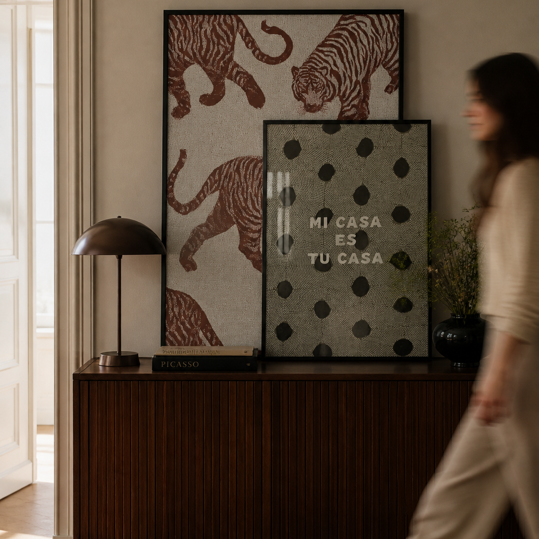 Woman walking past a wooden cabinet with decorative items including framed pictures and a lamp.