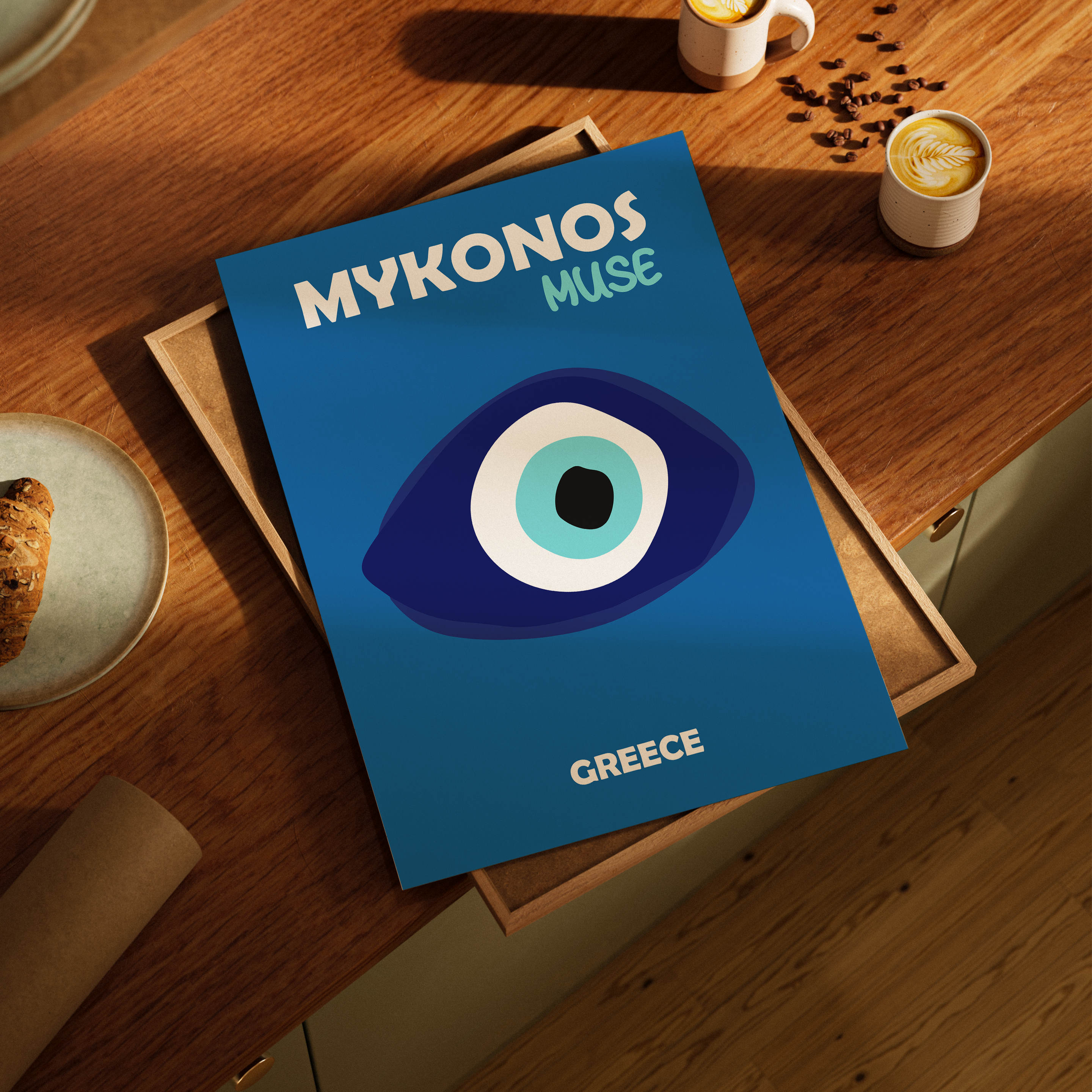 Blue poster titled 'Mykonos Muse Greece' on a wooden table with coffee cups and cookies.