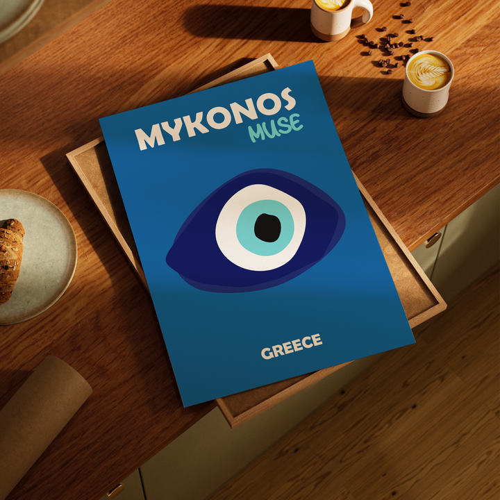 Blue poster titled 'Mykonos Muse Greece' on a wooden table with coffee cups and cookies.